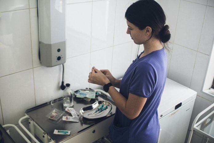 Επαγγελματίας υγείας προετοιμάζει σύριγγα σε κλινικό περιβάλλον